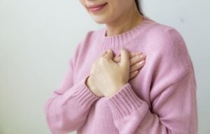 Woman gently placing both hands over her heart during a self compassion meditation