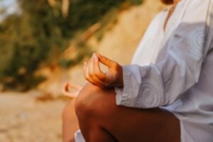 Person meditating outdoors with hands in a mindful mudra during a tonglen breathing practice