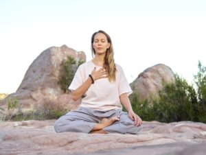 Woman meditating outdoors in a peaceful pose during a chakra meditation