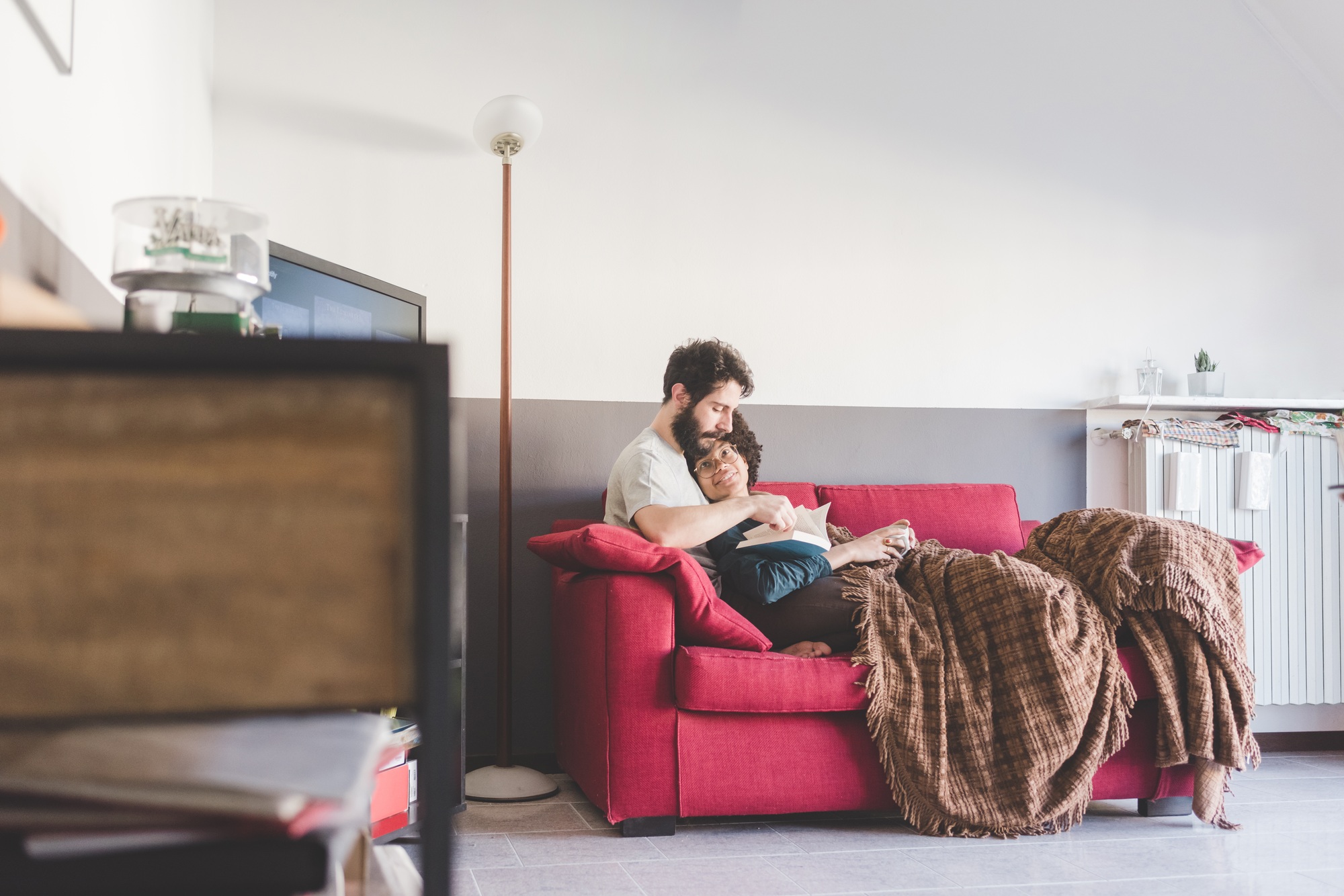 Young multiethnic couple hugging couch