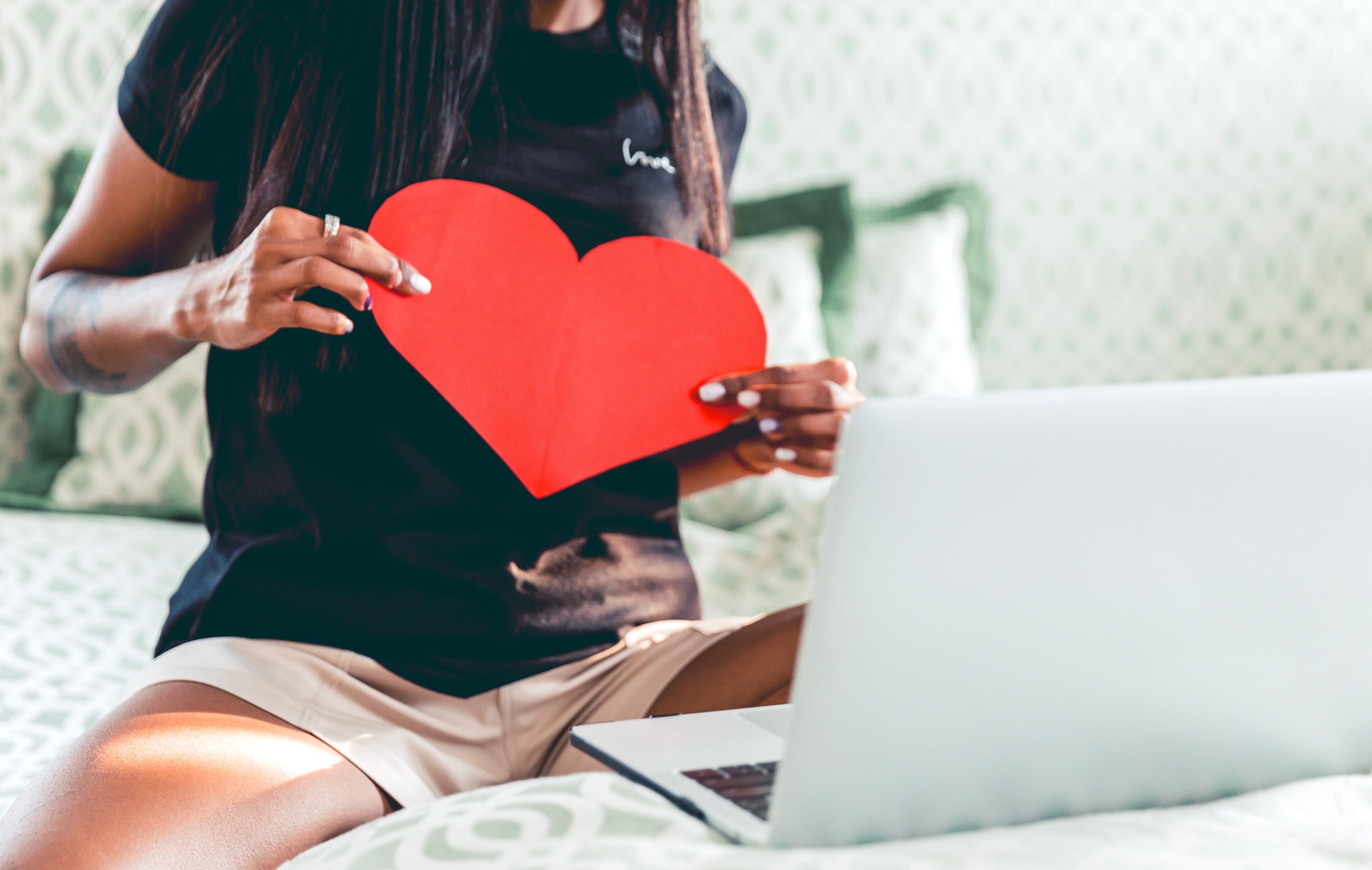 A woman chatting with her lover, holding a heart, love during COVID, long distance relationship