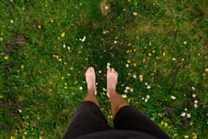 Bare feet standing in grass, practicing a grounding technique for anxiety
