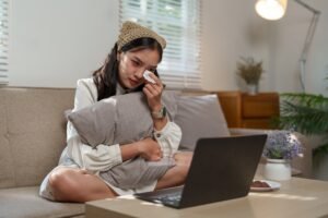 Sad woman wiping tears while watching a heartbreaking movie or receiving distressing news on her lap