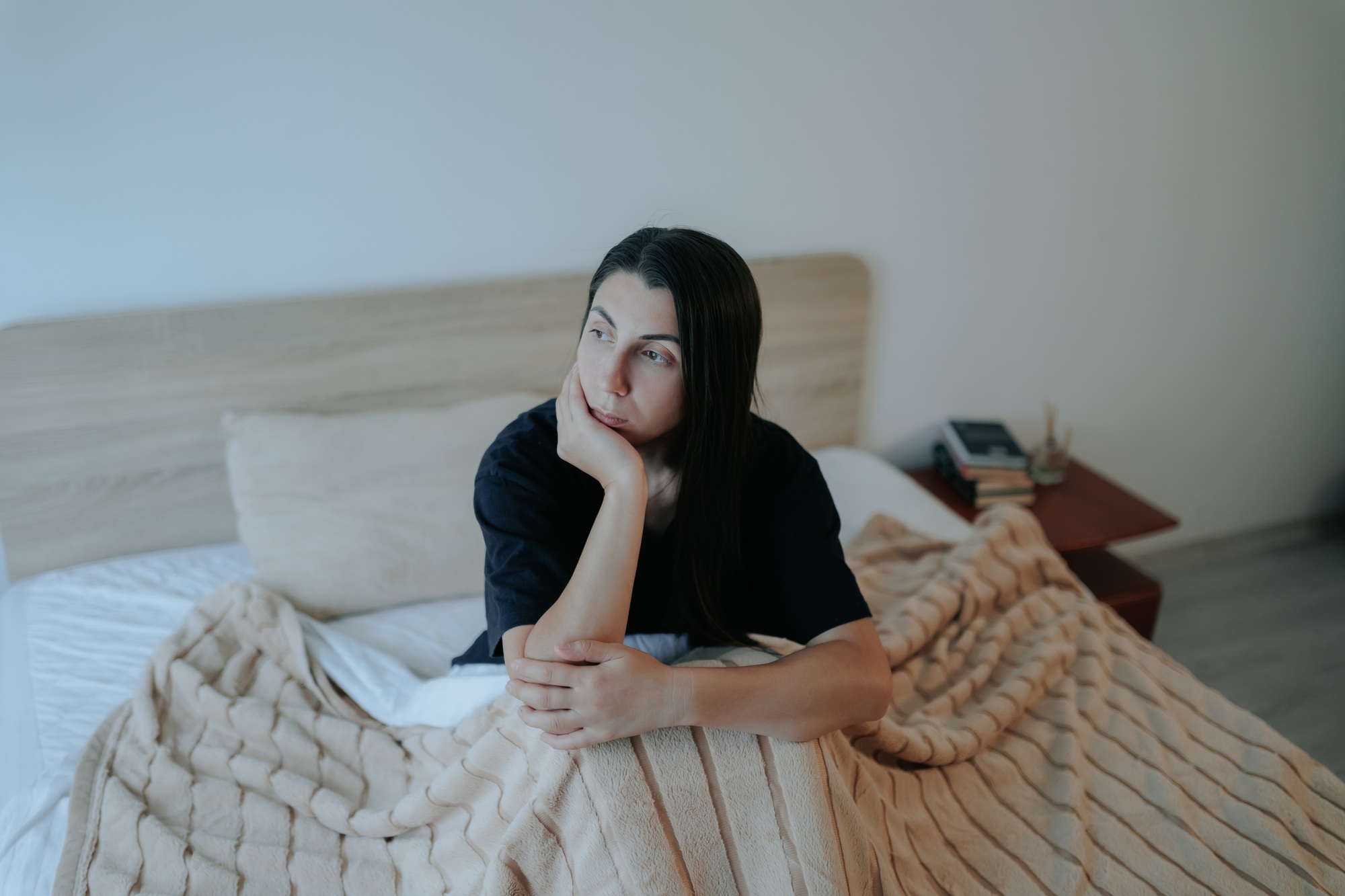 Sad Young Woman Sitting on Bed, Struggling with Depression at Night