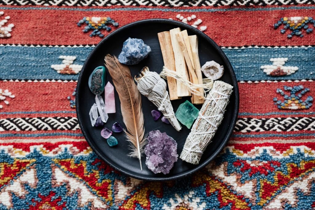 A bundle of dried white sage beside clear quartz and amethyst crystals, laid out on a cloth ready for smudging