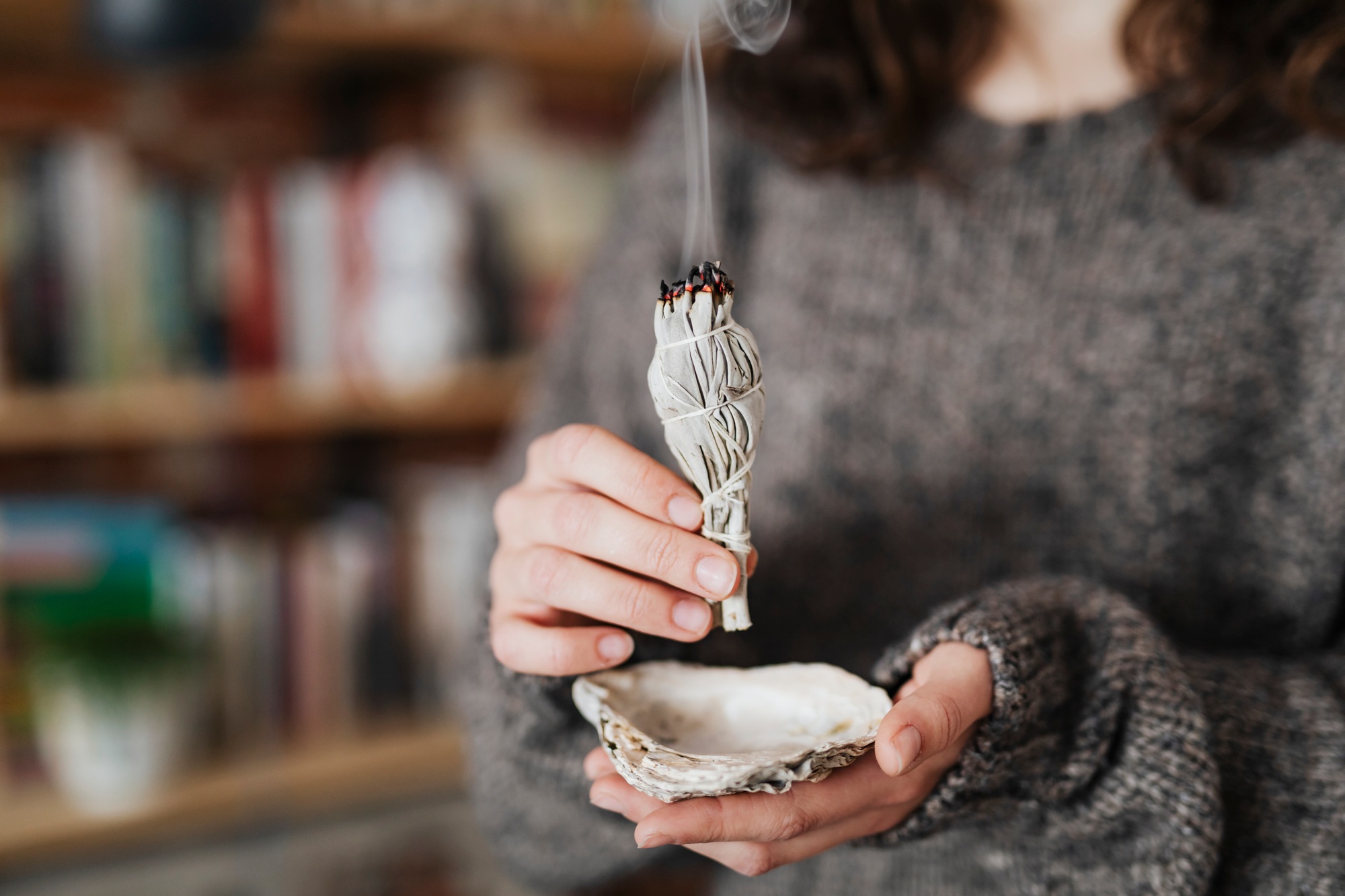 Woman burning sage smudge to cleanse the house