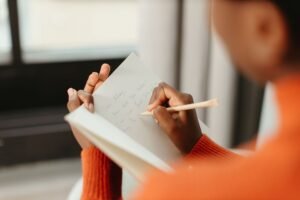 Hand writing reflectively in a journal, illustrating therapy journal prompts grounded in neuroscience and somatic wisdom