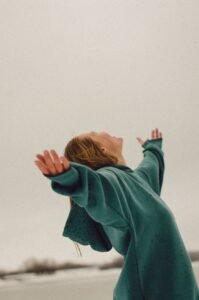 Person with arms outstretched facing an open sky, representing release and letting go in meditation