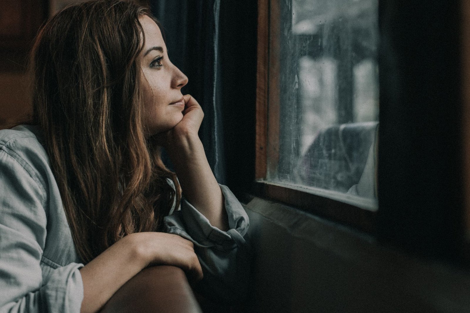 Woman gazing pensively out a window, reflecting on hidden barriers to vulnerability