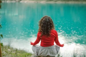 Woman sitting peacefully by water during a short guided meditation practice