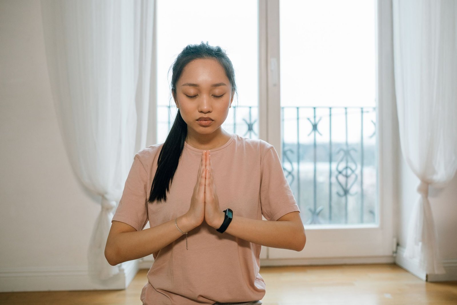 Woman with hands in prayer position practicing circular breathwork indoors