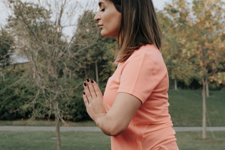 Woman practicing a deep breathing exercise outdoors for stress relief