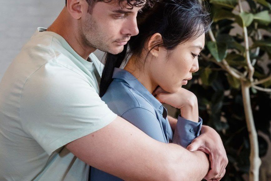 Man comforting his partner with a gentle embrace, responding to her need for reassurance